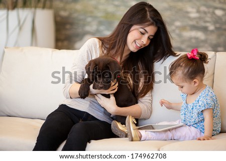 Pretty young babysitter looking after a puppy and a little girl