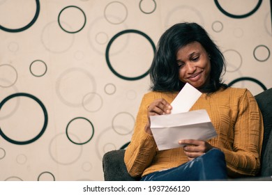 Pretty Young Black Woman Opening Up An Envelope And Taking Out A Letter