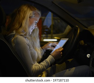 Pretty Young Blond Woman With Tablet Computer In The Car At Night