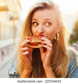 Pretty Young Blonde Funny Woman Eating Hamburger Outdoor On The Street 