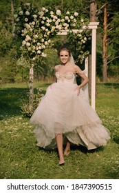 Pretty young bride on beautiful background. Slim and gorgeous woman. Natural colors. Wedding day. Beautiful dress. Fresh flowers. Green grass. Details