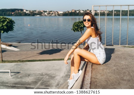 Pretty young brunette girl with long hair relaxing outdoor in the park near lake