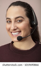 Pretty Young Call Center Operator Or Customer Services Representative Wearing A Headset Looking At The Camera With A Beaming Warm Friendly Smile