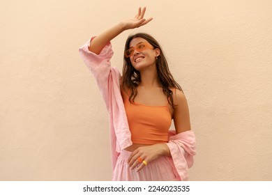 Pretty young caucasian woman looks away laughing streches hand up spends time outside. Brunette wears casual spring clothes. Leisure lifestyle concept.  - Shutterstock ID 2246023535