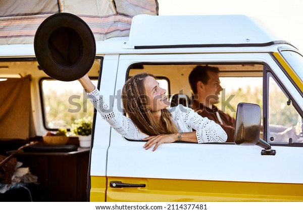 Pretty young Caucasian woman, traveler on road trip\
with husband,get out of camping van window in the morning. Cosy\
comfortable setup in camper van. Millennial travel trend, adventure\
on the road.