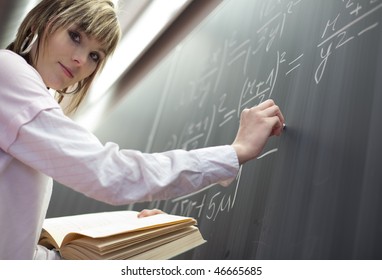 Pretty Young College Student Writing On The Chalkboard/blackboard During A Math Class