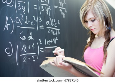 Pretty Young College Student Writing On The Chalkboard/blackboard During A Math Class (shallow DOF; Color Toned Image)