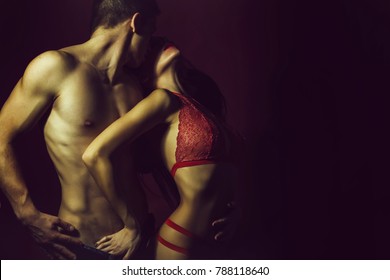 Pretty Young Couple Of Undressed Sensual Woman With Beautiful Straight Body In Red Lace Erotic Lingerie With Muscular Man Posing Indoor On Dark Purple Background, Horizontal Picture