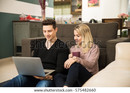 Pretty young couple using a laptop computer and relaxing together at home