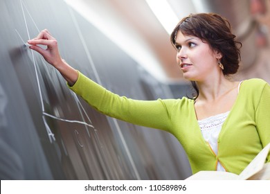 Pretty Young Elementary School/college Teacher Writing On The Chalkboard/blackboard During A Math Class (color Toned Image; Shallow DOF)