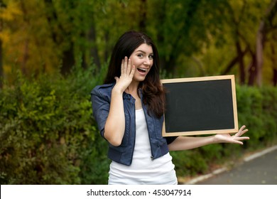 Pretty young excited woman holding empty blank