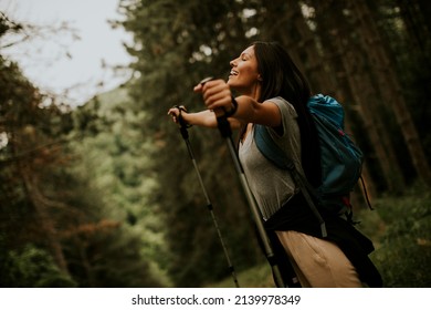 Pretty young female backpacker woman enjoying green beautiful forest around her