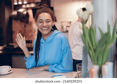 Pretty Young Female Bartender With Piercing Smiling At Counter And Waving Hand. Portrait