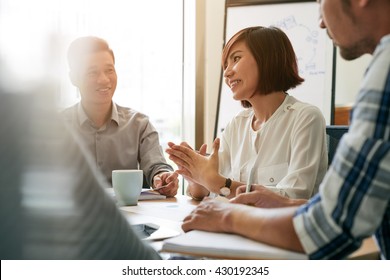 Pretty Young Female Entrepreneur Talking To Her Employees At Meeting