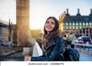 Pretty, young, female London traveler tourist enjoys the view next to the Big Ben clocktower touring a sightseeing city trip
