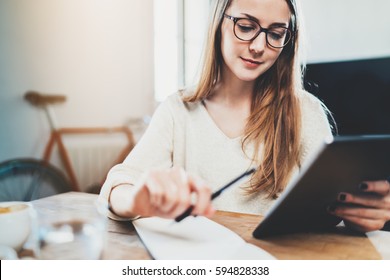 Pretty young female manager using modern digital tablet at office, smiling hipster girl working at home interior via tablet pc, attractive businesswoman sitting at vintage loft during a break  - Powered by Shutterstock