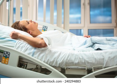 Pretty, young, female patient in a modern hospital room. Getting better fast after a surgery - pensive yet positive, thinking ahead, making plans (shallow DOF; color toned image) - Powered by Shutterstock