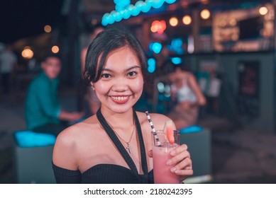 A Pretty Young FIlipino Woman Enjoying A Watermelon Shake At An Outdoor Bar. A Young Person Drinking Non-alcoholic Drinks. Nightlife Scene.