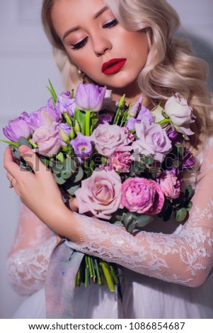 Pretty young girl. Blonde woman with luxurious long curly hair. Bride's morning. Taking wedding bouquet in hands