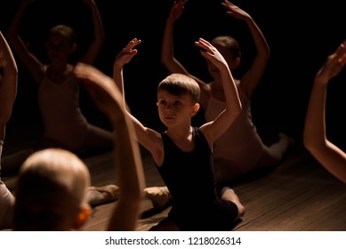 Pretty young girl and boy sitting on stage having stretching and training for ballet dances.