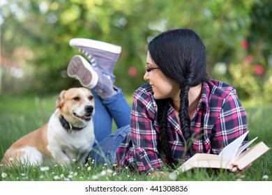 Pretty young girl in happy moment with her dog in grass in park