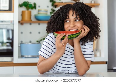 Pretty young girl holding slice of watermelon in front of her face.