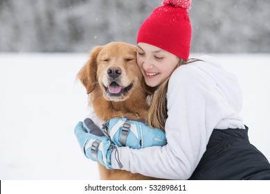 Pretty Young Girl Hugging Her Golden Retriever Dog In The Snow