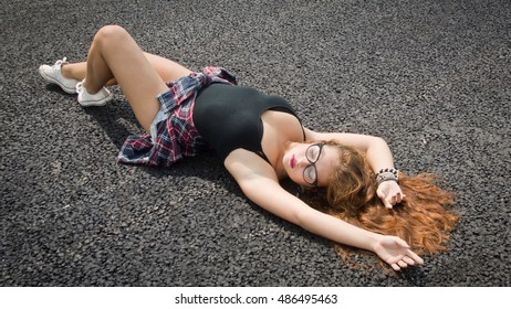 A Pretty Young Girl Laying On Asphalt
 