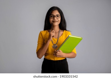 Pretty young girl posing with the book on grey background - Shutterstock ID 1903331542