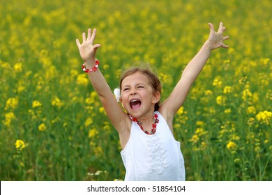 Pretty young girl screaming with delight surrounded by rapeseed flowers
