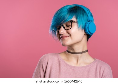 Pretty Young Girl With Turquoise Hair Having Fun, Smiling, Dancing With Blue Headphones In Studio On Colorful Background. Music, Dance, Radio Concept.