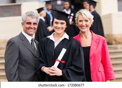pretty young graduate with happy parents at graduation ceremony