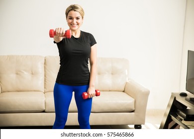 Pretty Young Hispanic Woman Lifting Weights And Working Out At Home