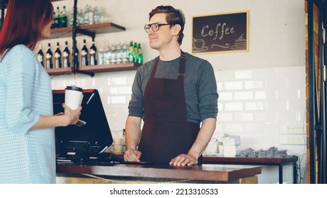 Pretty Young Lady Is Buying Takeaway Coffe In Coffee-shop And Paying With Smartphone Making Contactless Payment. Modern Technology, Conversation And Banking Concept.