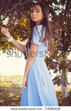 Pretty young lady dressed in a vintage long dress in a blue cage is enjoying a time in a autumn garden  