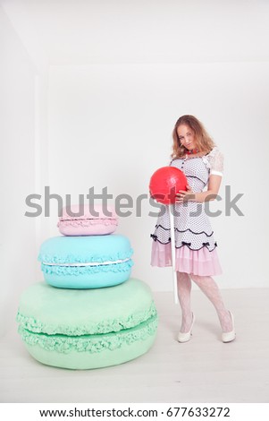 pretty young lady in polka dot pin up dress with giant sweets in white background studio 