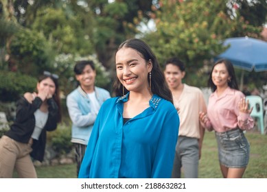 A Pretty Young Lady Posing For The Camera With Four Other Friends Behind. A Charismatic Female Leader With Her Team. Outdoor Scene.