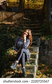 Pretty Young Lady Is Sitting On The Stairs At Sunset In Beautiful Autumn Forest. Colorful Autumn Landscape With Alone Girl In Dress And Fall Leaves. Travel And Adventure In Europe. Grza, Serbia.