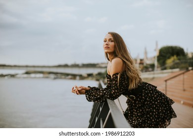 Pretty Young Long Hair Brunette Woman Standing On The Riverside