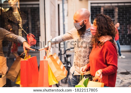 Pretty young man pointing to shop window to show clothing item his likes to his girlfriend - Beautiful young couple enjoying in shopping, having fun together, with the face mask -  ストックフォト © 