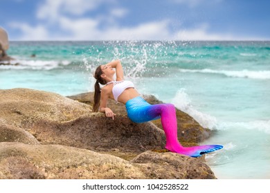 Pretty Young Mermaid Lies With Fin On A Rock In The Sun