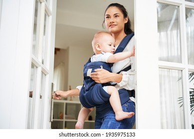 Pretty Young Mixed-race Woman Opening Entrance Door And Leaving House With Baby Boy In Carrier