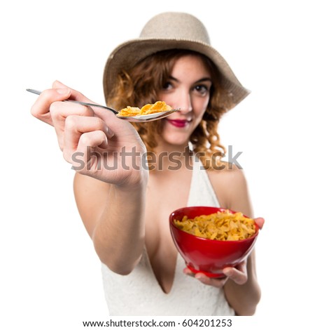 Pretty young model woman in swimsuit eating cereals from a bowl