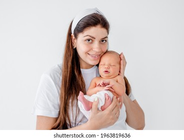 Pretty Young Mother Holding In Her Hands Adorable Newborn Baby, Looking At The Camera And Smiling. Beautiful Portrait Of Mom Anf Infant Child At Home. Girl With Her Little Kid Isolated On White