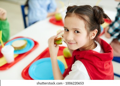 Pretty young schoolgirl eating sandwich at lunch break after classes - Powered by Shutterstock