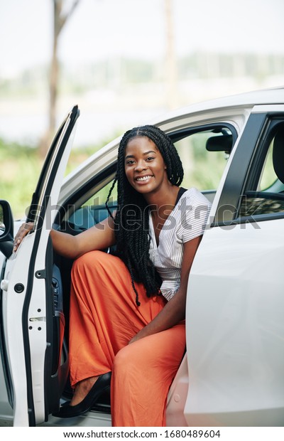 Pretty young smiling Black woman with dreadlocks\
sitting in her new car