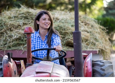 Pretty young smiling woman farmer driving tractor with trailer full of hay on farm woman veterinarian in front of piglets in stable - Powered by Shutterstock