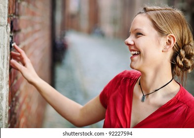 Pretty Young Smiling Woman Ringing At The Door Bell