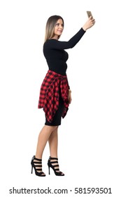 Pretty Young Stylish Woman In Black Dress Taking Selfie Photo With Mobile Phone. Full Body Length Isolated Over White Studio Background. 