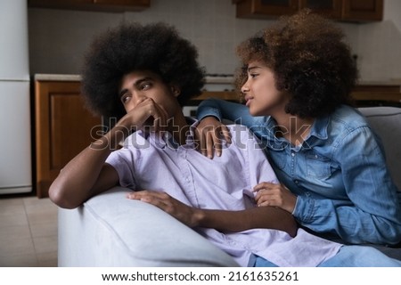 Pretty young teen African girlfriend saying sorry after row, quarrel, giving support, sympathy, love to offended hurt boyfriend, hugging, cuddling silent cold guy on couch. Relationship problems Stock photo © 